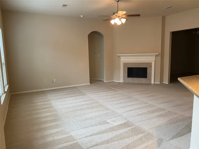 a view of an empty room with chandelier fan and fireplace