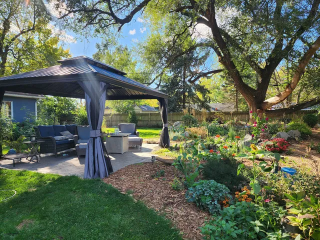 a view of a patio with table and chairs potted plants and large tree