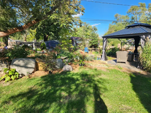 a backyard of a house with table and chairs under an umbrella