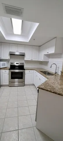 a kitchen with granite countertop a stove a sink and a microwave