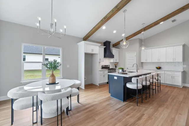 a kitchen with a dining table chairs wooden floor stainless steel appliances and cabinets