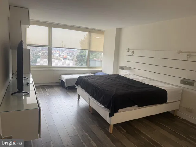 a bedroom with a bed lamp and a large window