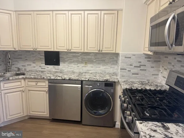 a kitchen with granite countertop a sink a stove and cabinets