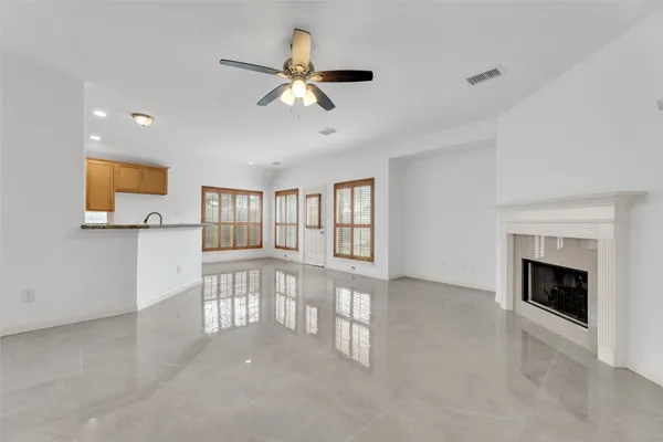 a view of an empty room with chandelier fan