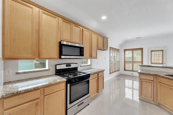 a kitchen with stainless steel appliances granite countertop a stove a sink and a microwave