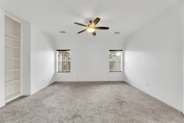 an empty room with windows and fan