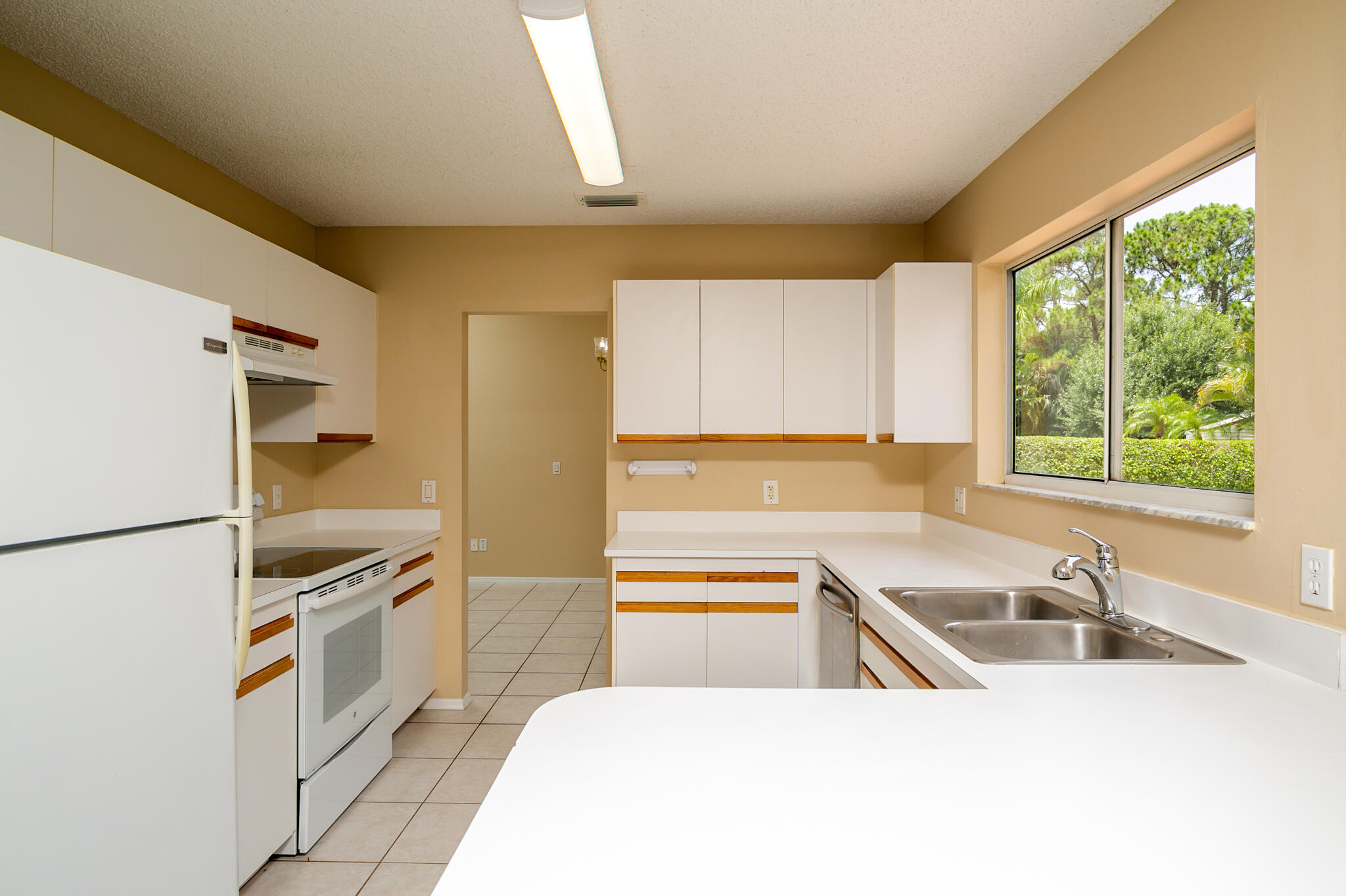 2904 Southeast Bella Road Port St. Lucie, FL 34984 - Photo 14 of 30 a kitchen with a sink a counter top space stainless steel appliances cabinets and a large window