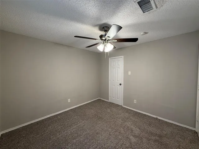 an empty room with a chandelier fan and windows