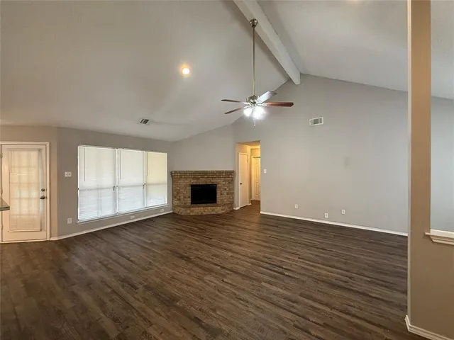 an empty room with wooden floor and fireplace