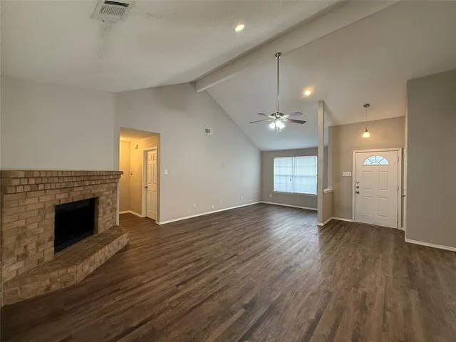 an empty room with wooden floor fireplace and windows