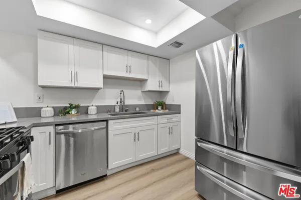 a kitchen with stainless steel appliances granite countertop a refrigerator sink and white cabinets