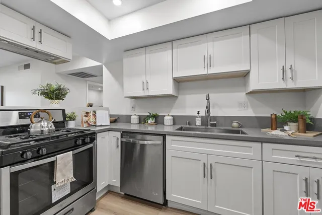 a kitchen with stainless steel appliances granite countertop white cabinets and a stove