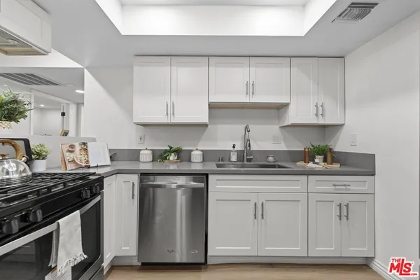 a kitchen with granite countertop white cabinets and stainless steel appliances
