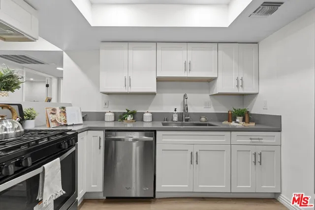 a kitchen with granite countertop white cabinets and stainless steel appliances