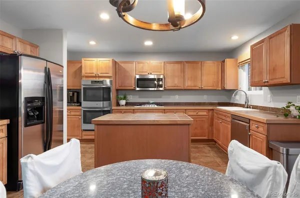 a kitchen with stainless steel appliances granite countertop a sink a stove a refrigerator a microwave a dining table and chairs