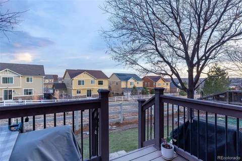 a view of a brick house with large trees and a wooden fence