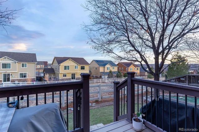 a view of a brick house with large trees and a wooden fence