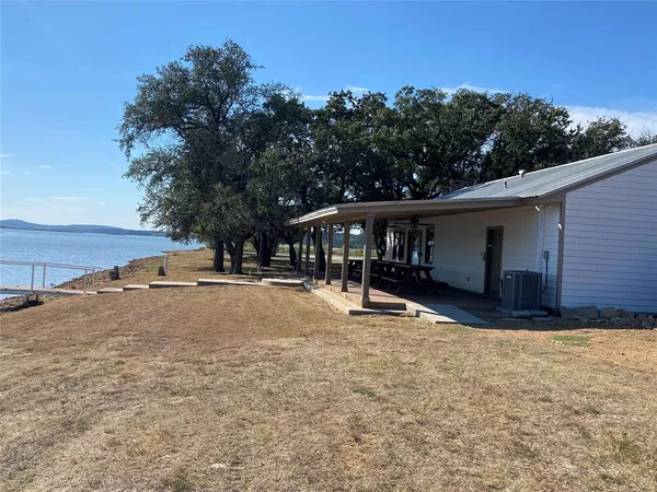 a view of house with outdoor space and trees in the background