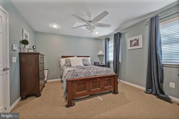 a living room with a bed and ceiling fan