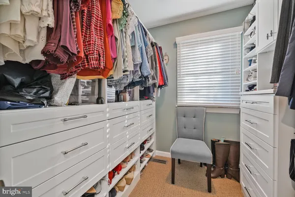 a view of walk in closet with clothes and shoes