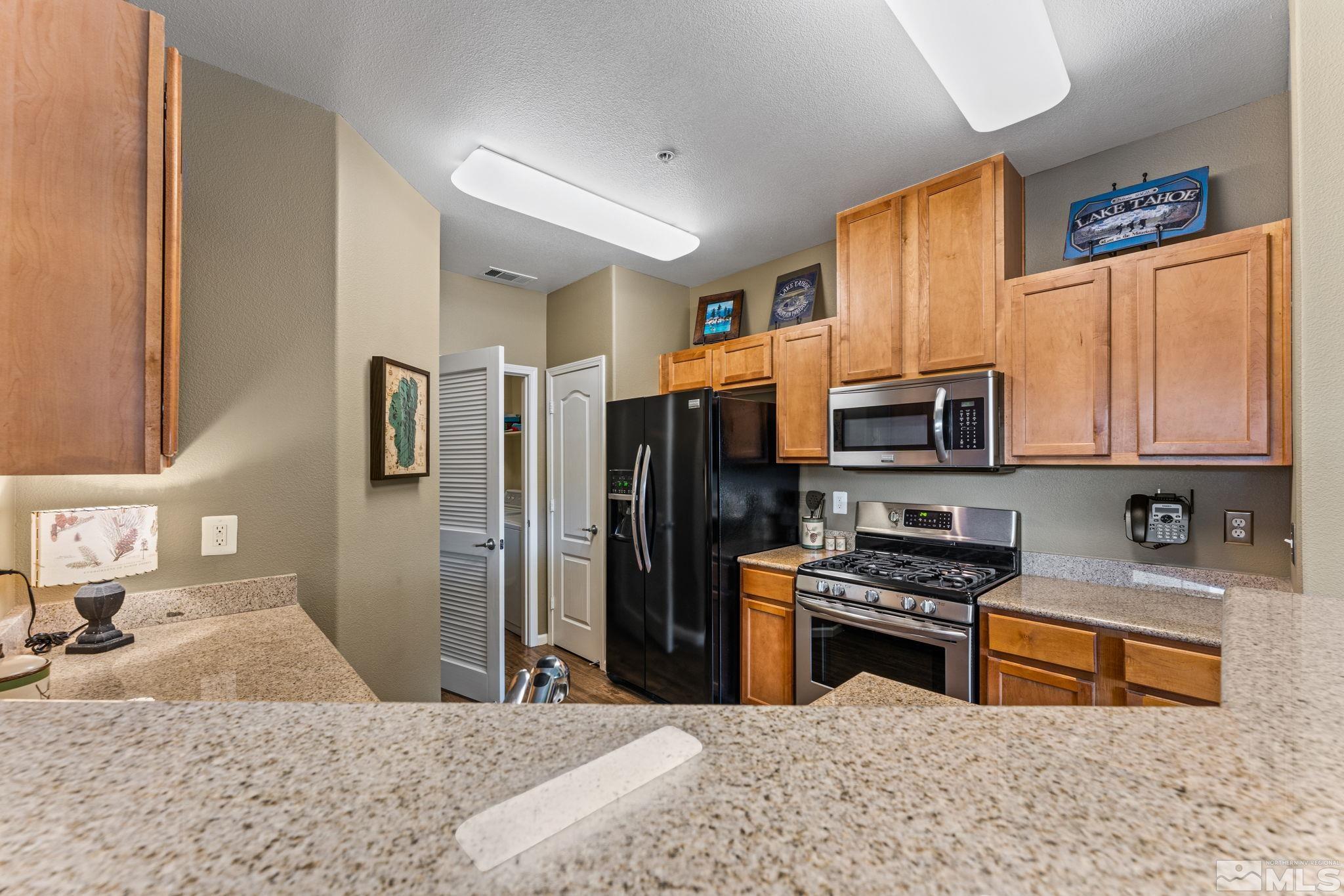 9050 Double R Boulevard, Unit 921 Reno, NV 89521 - Photo 17 of 39 a kitchen with stainless steel appliances granite countertop a stove a sink dishwasher a refrigerator and a microwave oven