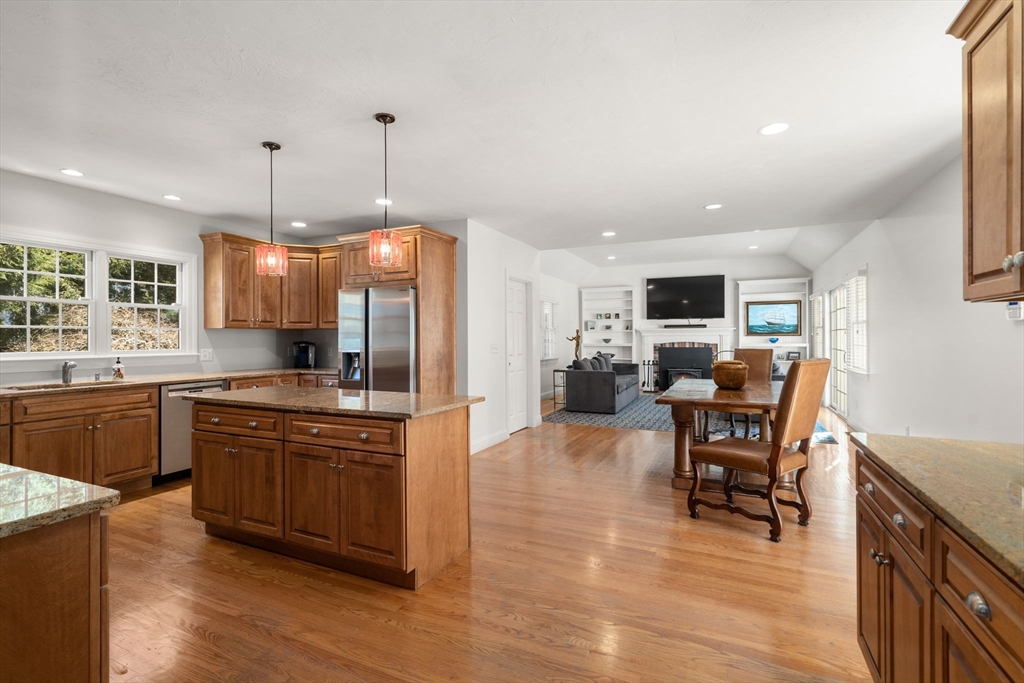36 Sherman's Bridge Road Wayland, MA 01778 - Photo 8 of 39 a kitchen with stainless steel appliances granite countertop a stove top oven a sink dishwasher a dining table and chairs with wooden floor
