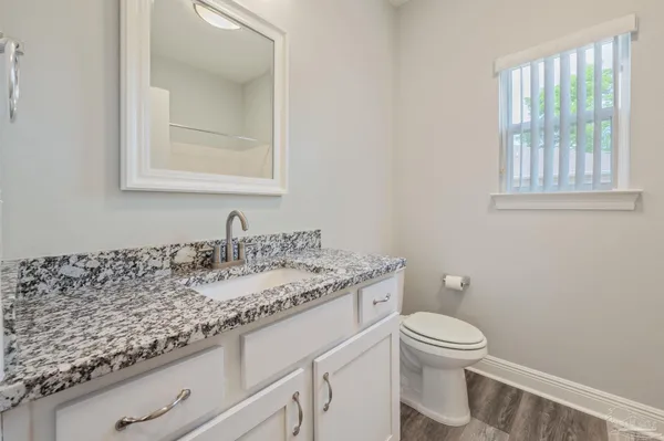 a bathroom with a granite countertop sink a toilet and a window