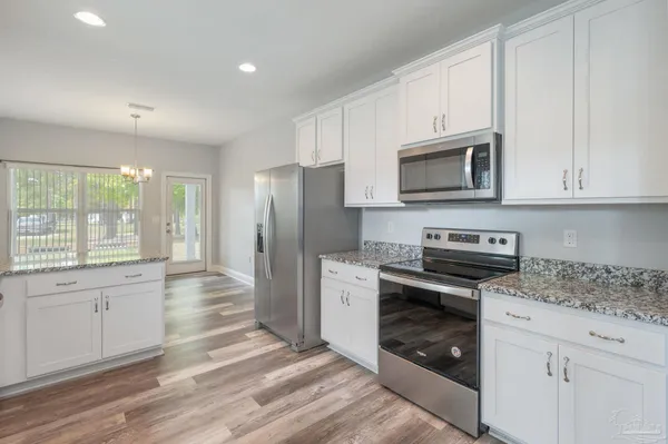 a kitchen with stainless steel appliances granite countertop a stove a refrigerator and a microwave