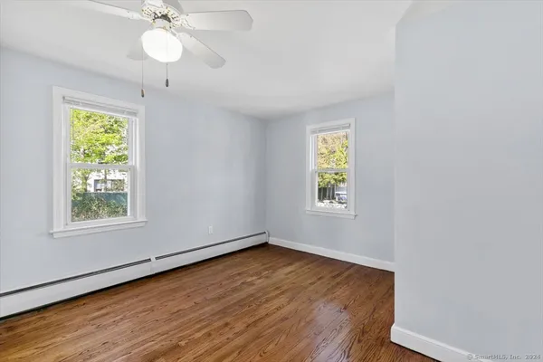 a view of an empty room with wooden floor and window
