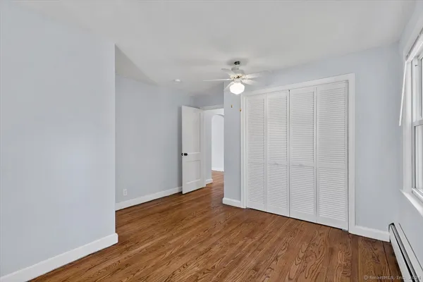 an empty room with wooden floor and fan
