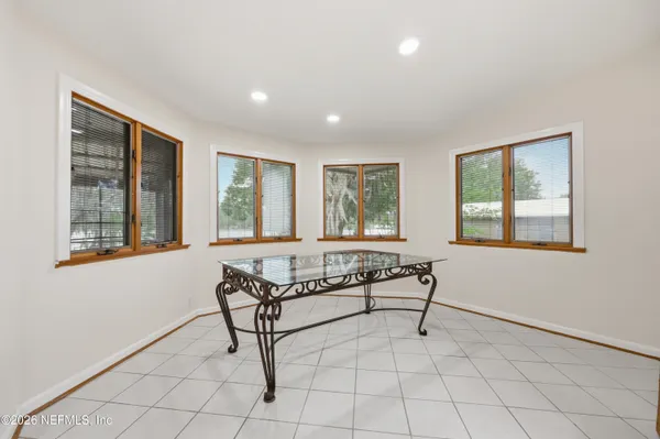 an empty room with wooden floor ceiling fan and windows