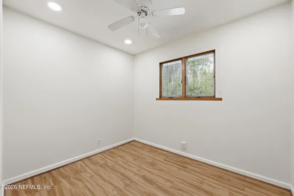 a view of empty room with wooden floor and fan