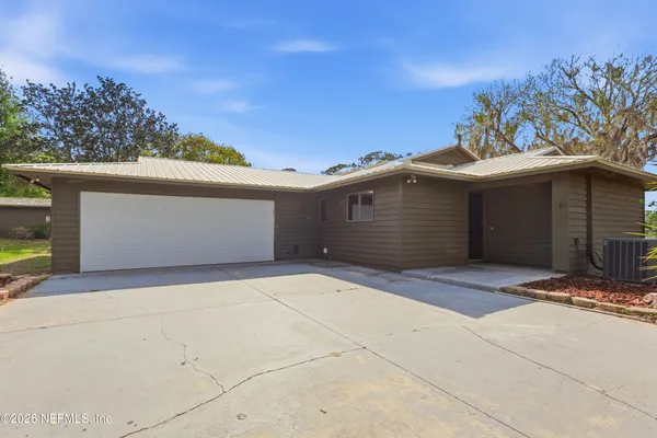 a view of an empty room with wooden floor and a kitchen