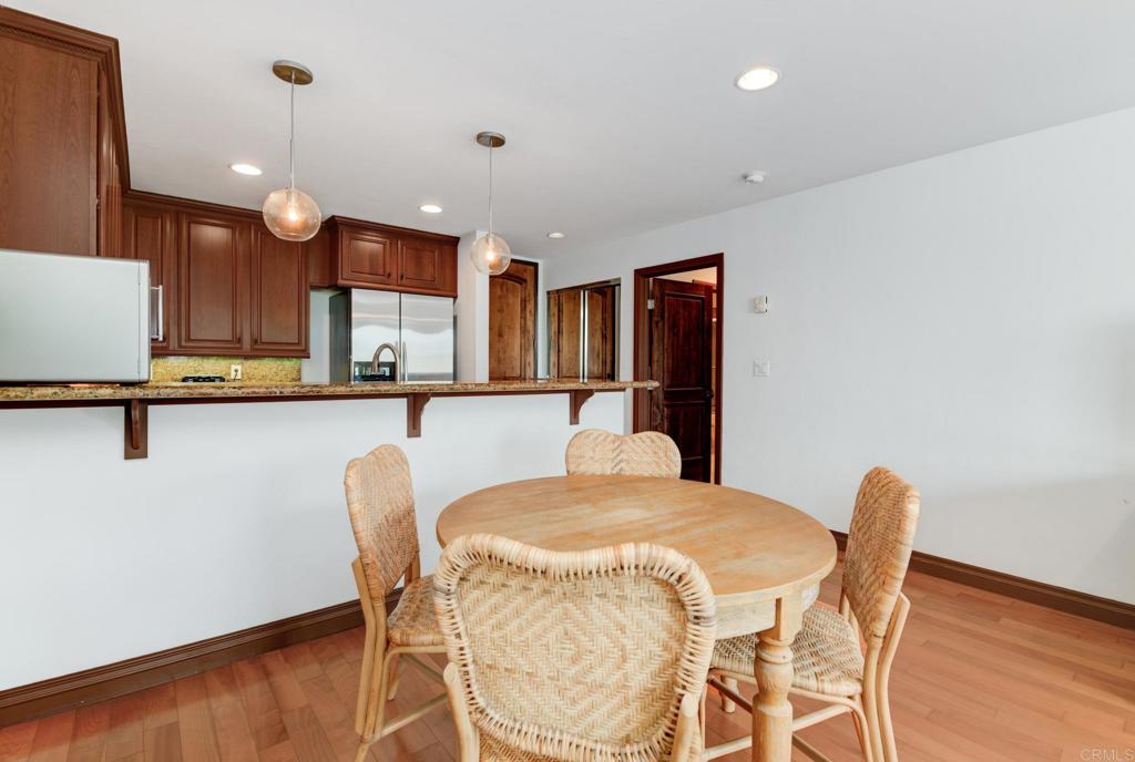 935 Genter Street, Unit 212 La Jolla, CA 92037 - Photo 11 of 23 a kitchen with stainless steel appliances kitchen island granite countertop a table chairs and a refrigerator
