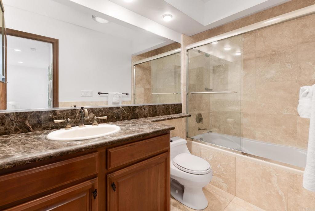 935 Genter Street, Unit 212 La Jolla, CA 92037 - Photo 19 of 23 a bathroom with a granite countertop sink toilet mirror and bathtub