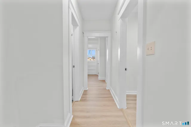 a view of a hallway with wooden floor and a bathroom