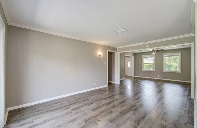 a view of an empty room with window and wooden floor