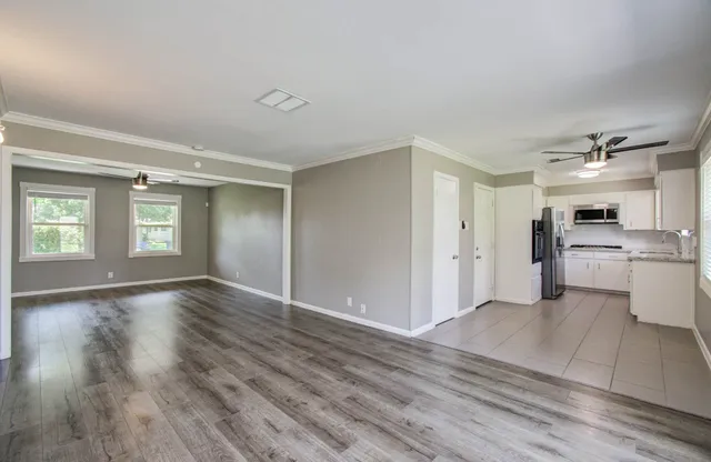a view of an empty room with window and wooden floor