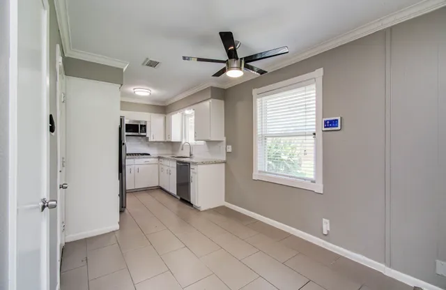 a kitchen with white cabinets and window