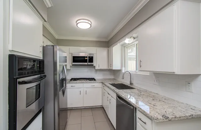 a kitchen with stainless steel appliances granite countertop a refrigerator a stove top oven a sink and dishwasher