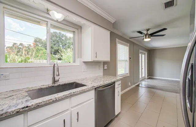 a kitchen with granite countertop a sink appliances cabinets and a large window