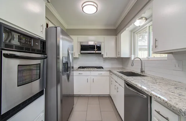 a kitchen with stainless steel appliances granite countertop a stove a sink and a microwave