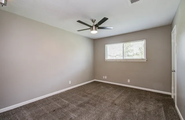 an empty room with a window and a fan