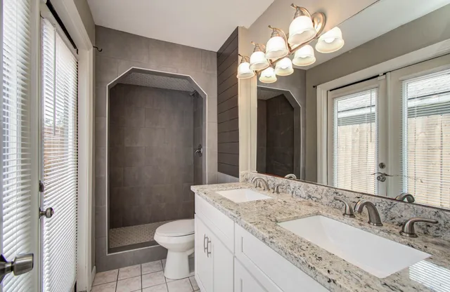 a bathroom with a granite countertop sink a toilet and a mirror
