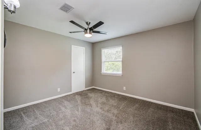 an empty room with a window and a fan