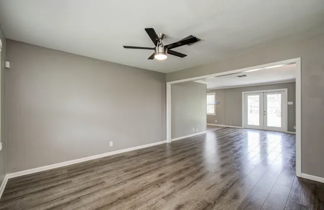 a view of empty room with wooden floor and fan