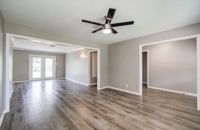 a view of empty room with wooden floor and ceiling fan