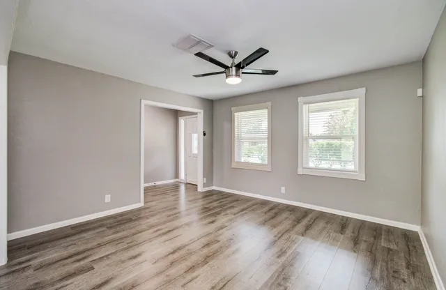 a view of an empty room with wooden floor and a window
