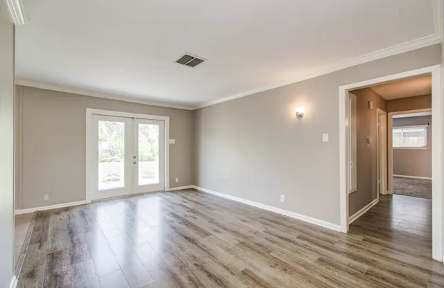 a view of an empty room with window and wooden floor