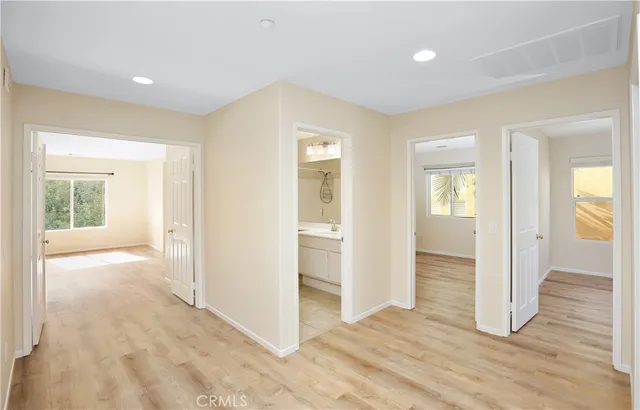 an empty room with wooden floor mirror and windows